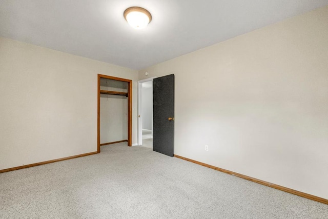 unfurnished bedroom with a closet, light colored carpet, and baseboards