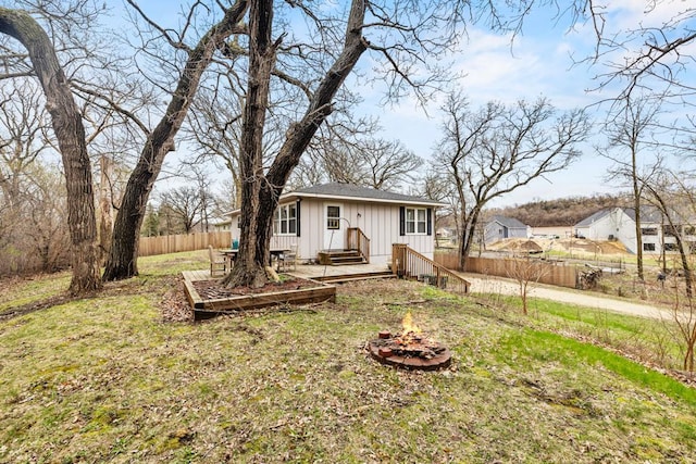 view of front of property featuring a front lawn, a fire pit, board and batten siding, and fence