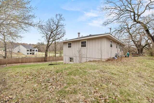 back of property featuring fence, board and batten siding, and a yard