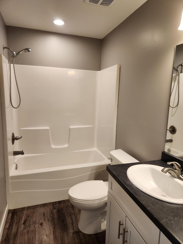 bathroom featuring toilet, wood finished floors, vanity, and washtub / shower combination