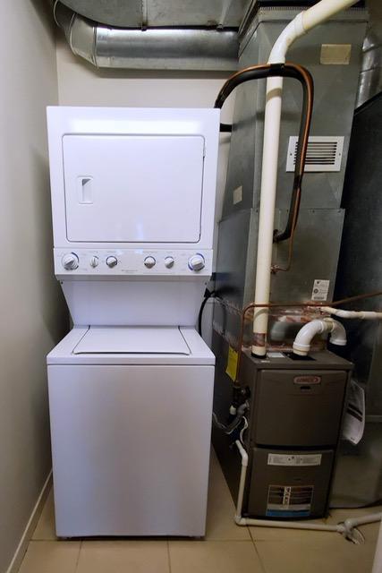1070 Grandview Ct NE Unit 413, Columbia Heights, MN 55421 - washroom with tile patterned floors, heating unit, and stacked washer and clothes dryer