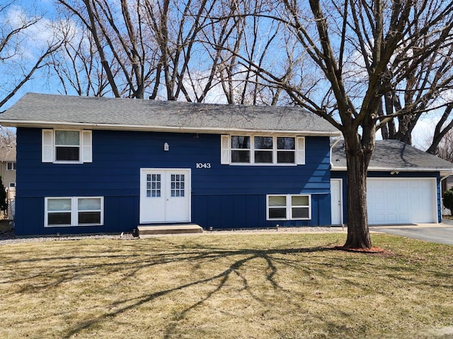 bi-level home with an attached garage, a front yard, and aphalt driveway