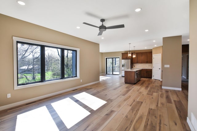 1504 14th Ave NE, Kasson, MN 55944 - unfurnished living room with light wood-style flooring, ceiling fan, baseboards, and recessed lighting