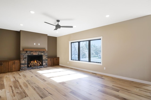 1504 14th Ave NE, Kasson, MN 55944 - unfurnished living room with light wood finished floors, ceiling fan, baseboards, a stone fireplace, and recessed lighting