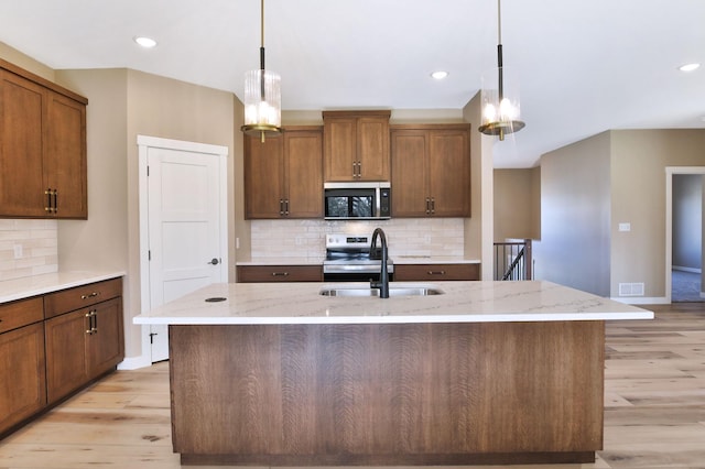 1504 14th Ave NE, Kasson, MN 55944 - kitchen featuring stainless steel appliances, a sink, light wood-style flooring, pendant lighting, and light stone countertops