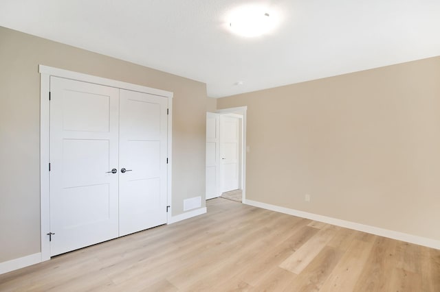 1504 14th Ave NE, Kasson, MN 55944 - unfurnished bedroom with baseboards, light wood finished floors, and a closet