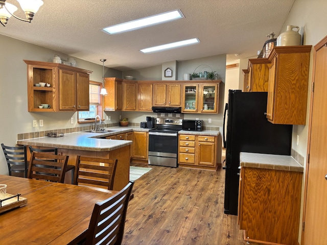 154 Pond Dr, Jackson, MN 56143 - kitchen with a peninsula, black appliances, a sink, lofted ceiling, and brown cabinets