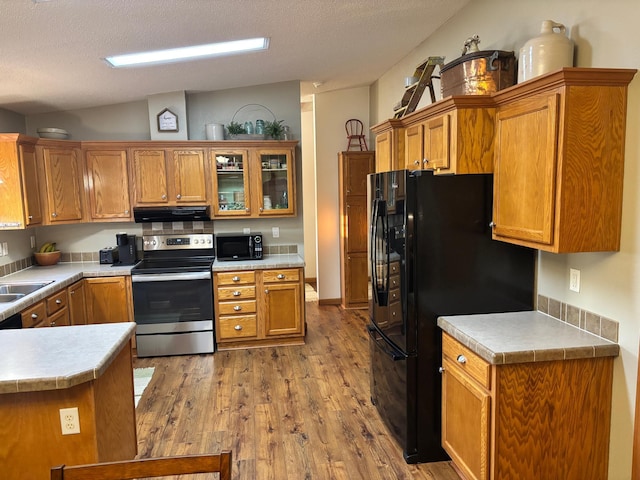 154 Pond Dr, Jackson, MN 56143 - kitchen with brown cabinetry, wood finished floors, range hood, and black appliances