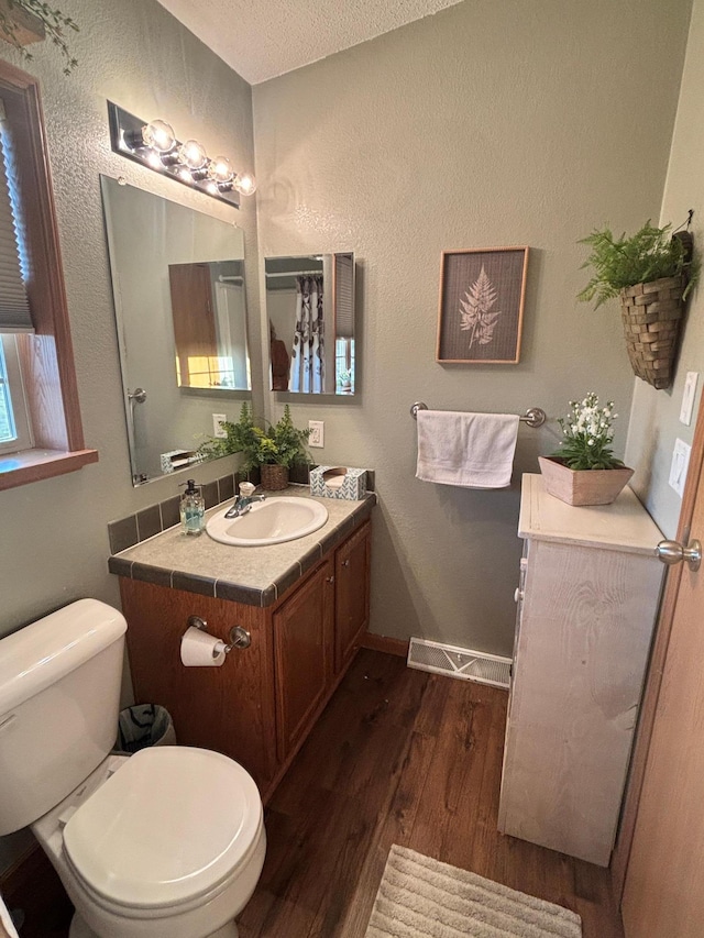 154 Pond Dr, Jackson, MN 56143 - bathroom featuring baseboards, toilet, a textured ceiling, vanity, and wood finished floors
