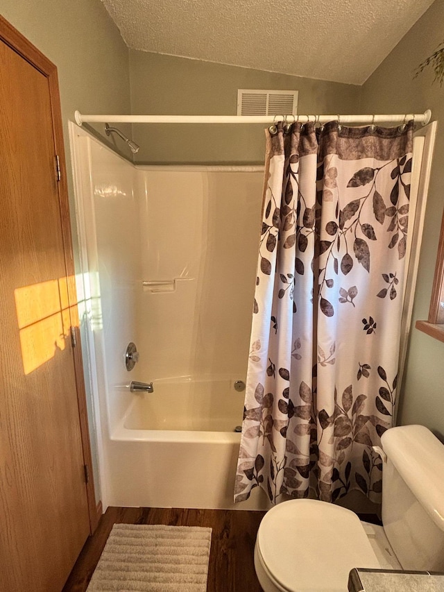 154 Pond Dr, Jackson, MN 56143 - full bath with a textured ceiling, visible vents, toilet, wood finished floors, and shower / bath combo with shower curtain
