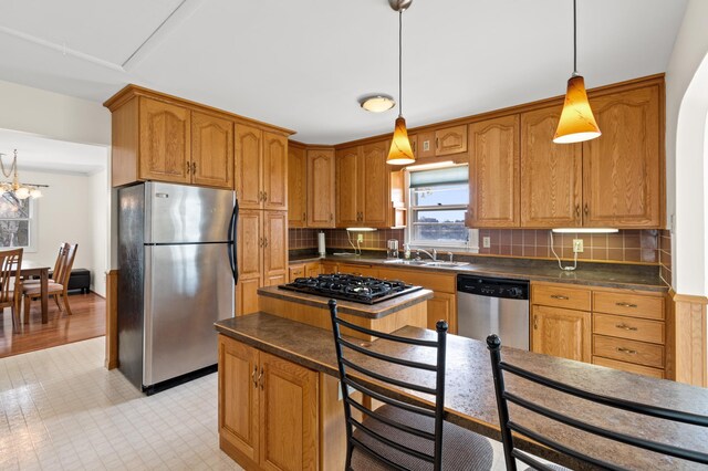 kitchen featuring dark countertops, a sink, appliances with stainless steel finishes, and tasteful backsplash