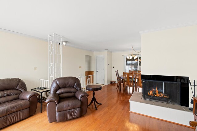 living room featuring crown molding, light wood finished floors, and a notable chandelier