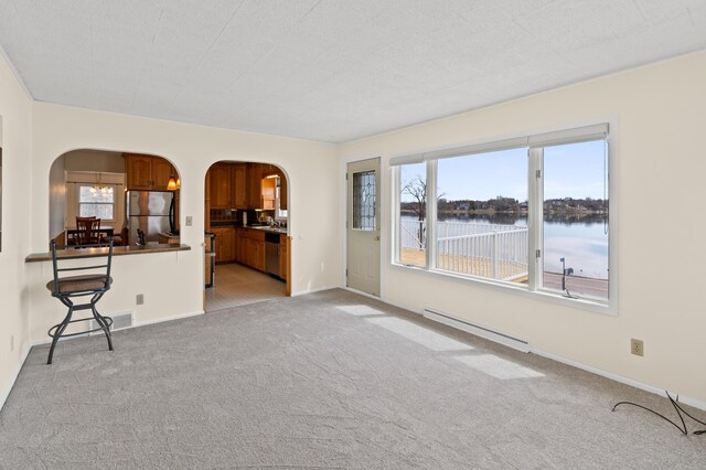 unfurnished living room featuring light colored carpet, a baseboard radiator, and arched walkways
