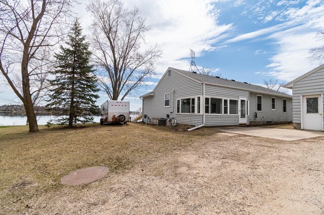 rear view of house featuring central air condition unit, roof with shingles, a water view, and a patio area
