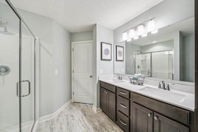 4271 Corn Silk Ln, Woodbury, MN 55129 - full bath featuring a stall shower, baseboards, a textured ceiling, and double vanity