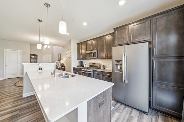 4271 Corn Silk Ln, Woodbury, MN 55129 - kitchen with stainless steel appliances, a sink, light wood finished floors, an island with sink, and dark brown cabinets