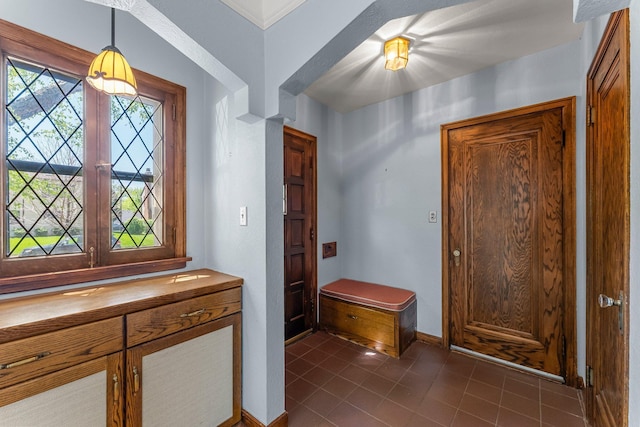 entrance foyer with dark tile patterned floors and baseboards