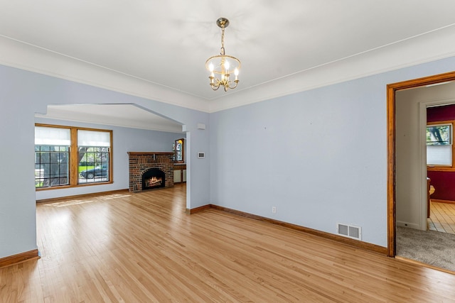 unfurnished living room with a chandelier, light wood-style flooring, and baseboards