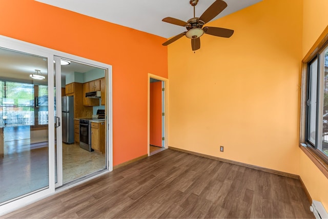 spare room featuring a baseboard radiator, dark wood-style flooring, ceiling fan, and baseboards