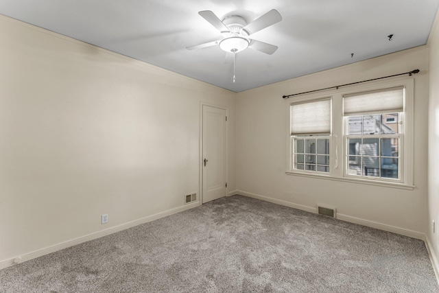 carpeted spare room featuring baseboards and a ceiling fan