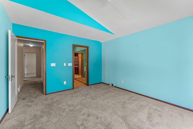 unfurnished bedroom featuring carpet floors, vaulted ceiling, and baseboards