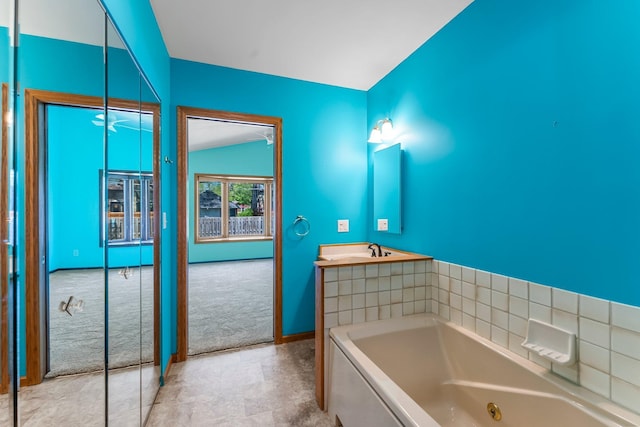 full bath featuring a tub with jets, baseboards, and a sink
