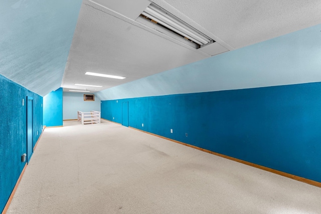 additional living space featuring lofted ceiling, a textured ceiling, carpet, and baseboards