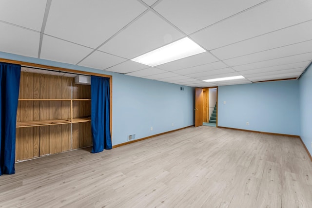 finished below grade area with wood finished floors, baseboards, stairs, and a paneled ceiling