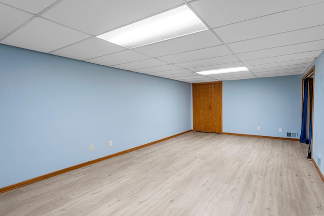unfurnished room featuring baseboards, light wood-style floors, and a paneled ceiling