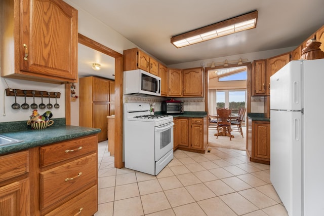 16227 Bay Dr, Pengilly, MN 55775 - kitchen featuring white appliances, dark countertops, brown cabinets, and backsplash