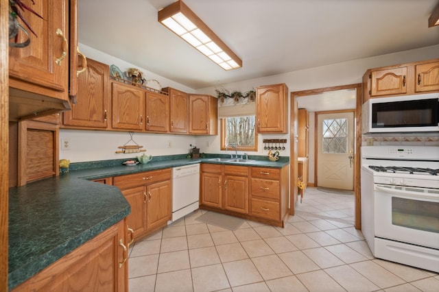 16227 Bay Dr, Pengilly, MN 55775 - kitchen featuring white appliances, dark countertops, a sink, light tile patterned floors, and brown cabinetry