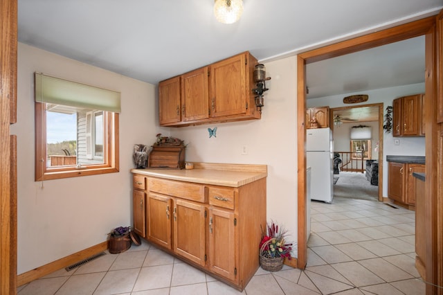 16227 Bay Dr, Pengilly, MN 55775 - kitchen with freestanding refrigerator, light tile patterned flooring, brown cabinetry, a ceiling fan, and baseboards