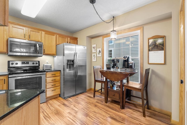 kitchen with a textured ceiling, pendant lighting, appliances with stainless steel finishes, baseboards, and light wood-style flooring