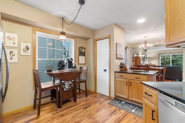 kitchen featuring dark countertops, appliances with stainless steel finishes, baseboards, a chandelier, and light wood-style flooring