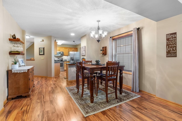 dining space featuring an inviting chandelier, baseboards, and light wood-type flooring