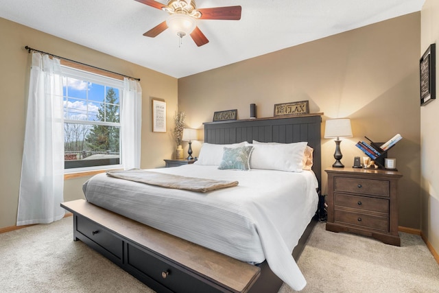 bedroom featuring light colored carpet, a ceiling fan, and baseboards