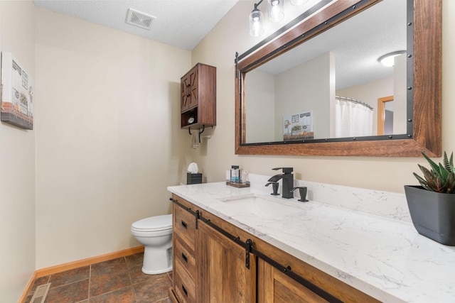 bathroom with vanity, toilet, a textured ceiling, baseboards, and visible vents