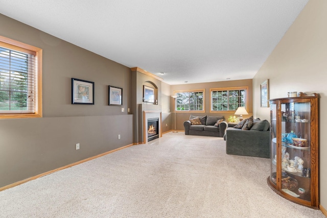 living room featuring carpet floors, baseboards, and a glass covered fireplace