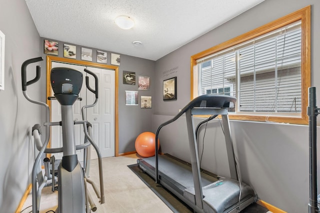workout area with carpet flooring, a textured ceiling, and baseboards