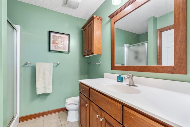 bathroom featuring a shower stall, tile patterned floors, vanity, baseboards, and toilet