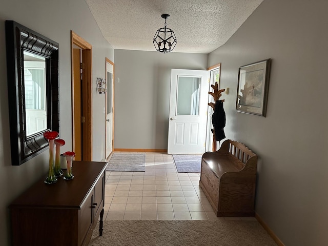 entryway with baseboards, a textured ceiling, and light tile patterned floors