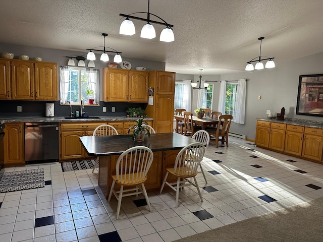 kitchen featuring dark countertops, a sink, dishwashing machine, and a textured ceiling