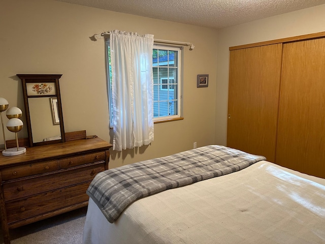 bedroom with a textured ceiling, carpet floors, and a closet