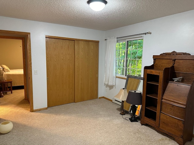 bedroom featuring a textured ceiling, baseboards, carpet, baseboard heating, and a closet