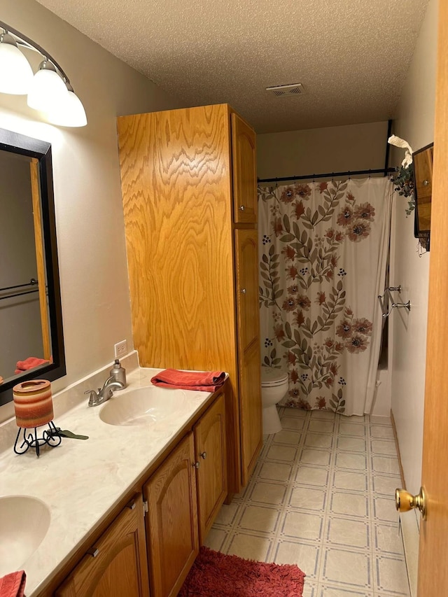 bathroom featuring a textured ceiling, visible vents, toilet, and a sink