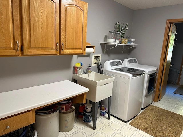 washroom with washing machine and dryer, a sink, light floors, and cabinet space