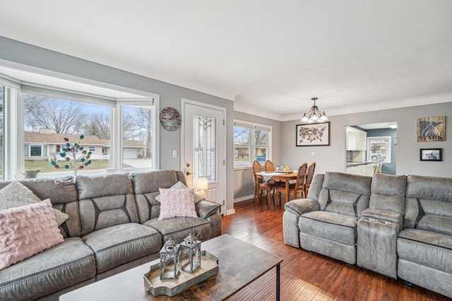 living area featuring baseboards, a chandelier, and dark wood-style flooring