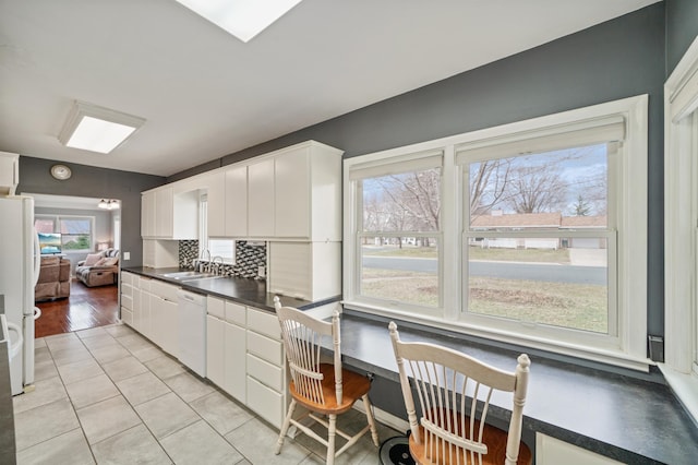 kitchen with dark countertops, white appliances, a sink, and plenty of natural light