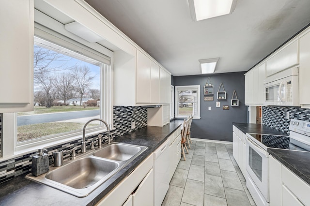 kitchen featuring tasteful backsplash, a healthy amount of sunlight, a sink, and white appliances