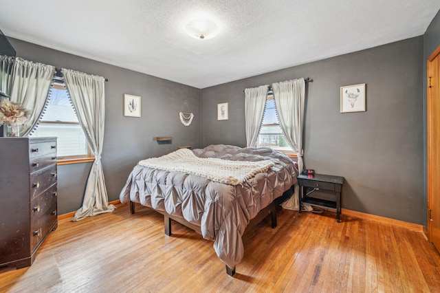 bedroom featuring wood-type flooring, baseboards, and multiple windows